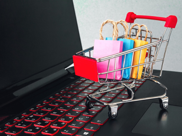 Online shopping / ecommerce and delivery service concept : Paper cartons with a shopping cart or trolley logo on a laptop keyboard, depicts customers order things from retailer sites via the internet._id1194050935