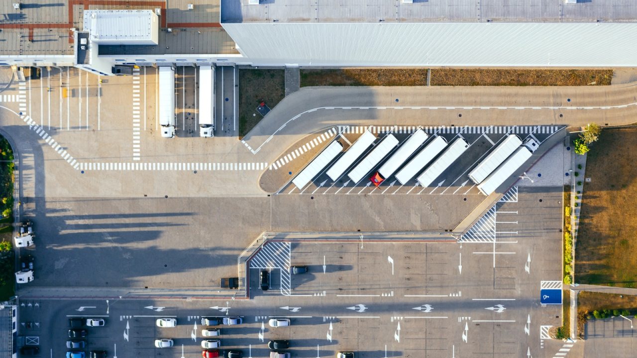 An aerial view of white trucks waiting to load up with cargo to distribute.