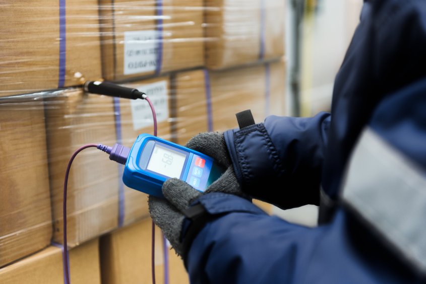 A warehouse worker monitors the temperature of inventory stored in a warehouse.
