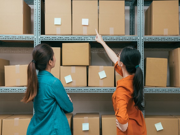 Back view photo of online shopping company office workers looking at shipping box and pointing order memo confirm warehouse stock with vintage retro film color_id671635150