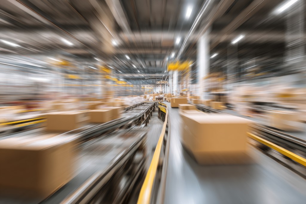 Packages move quickly along conveyor belts in a warehouse in a blur.