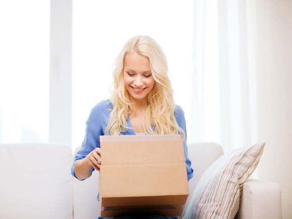 Transportation, post and people concept - smiling young woman opening cardboard box at home_id 228541339