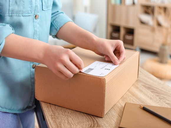 Young woman preparing parcel for client at home, closeup_2003066858