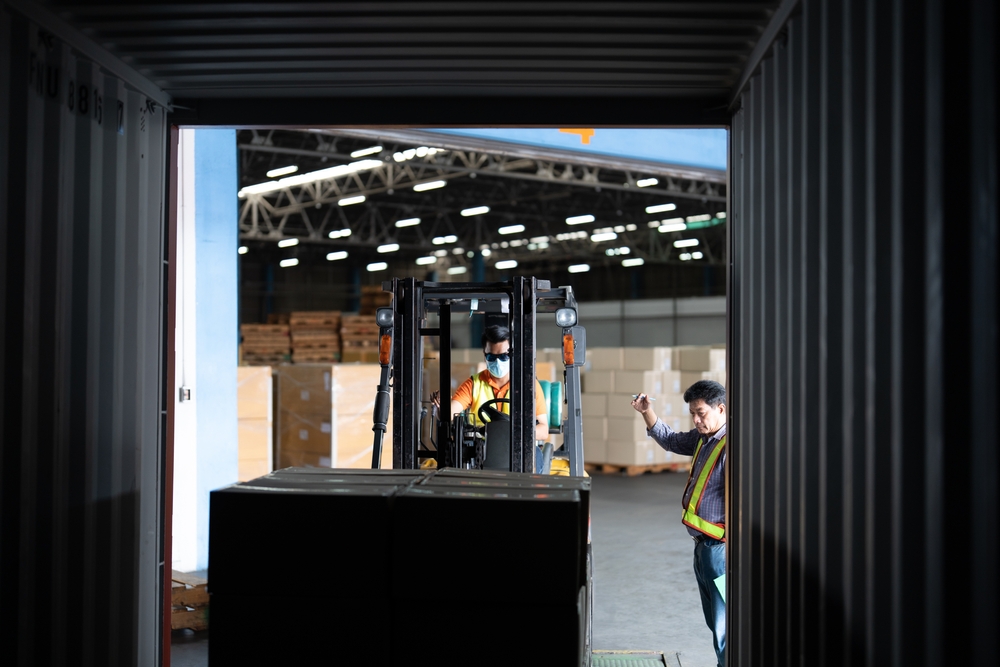 Warehouse worker open doors steel 40 feet container and ask forklift truck take out the carton box from 40 ft. container supervisor stand near by using paper clip checklist_id2212234379