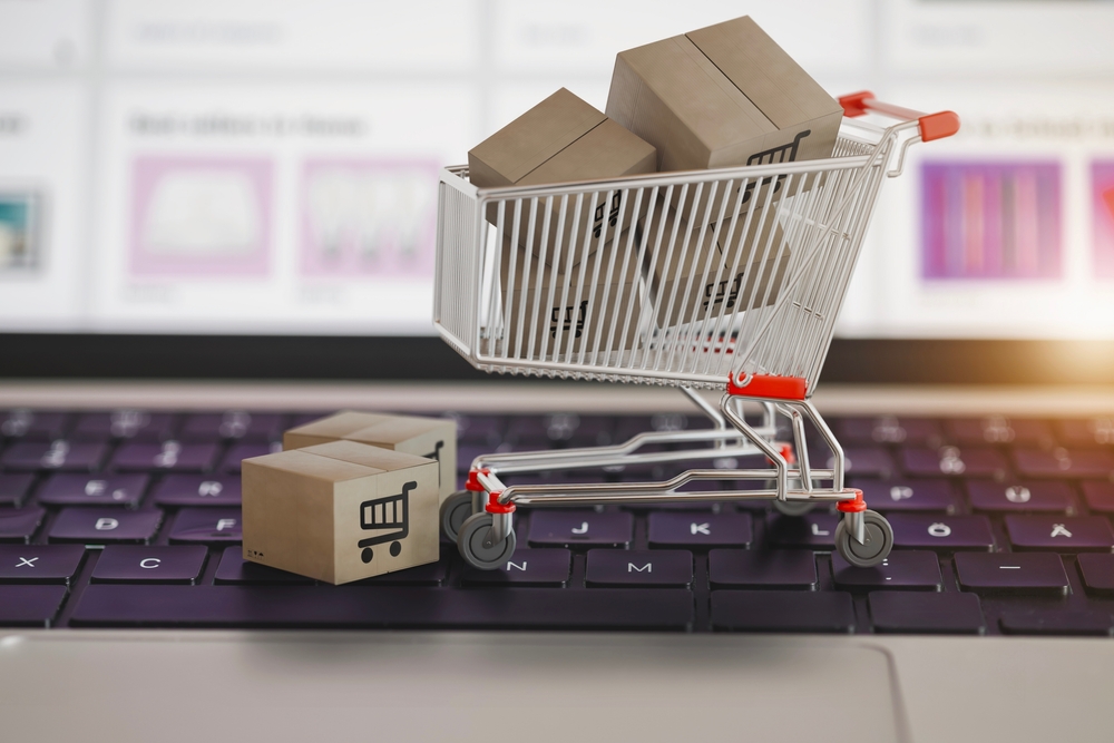 Shopping cart figurine full of boxes on a keyboard of a laptop