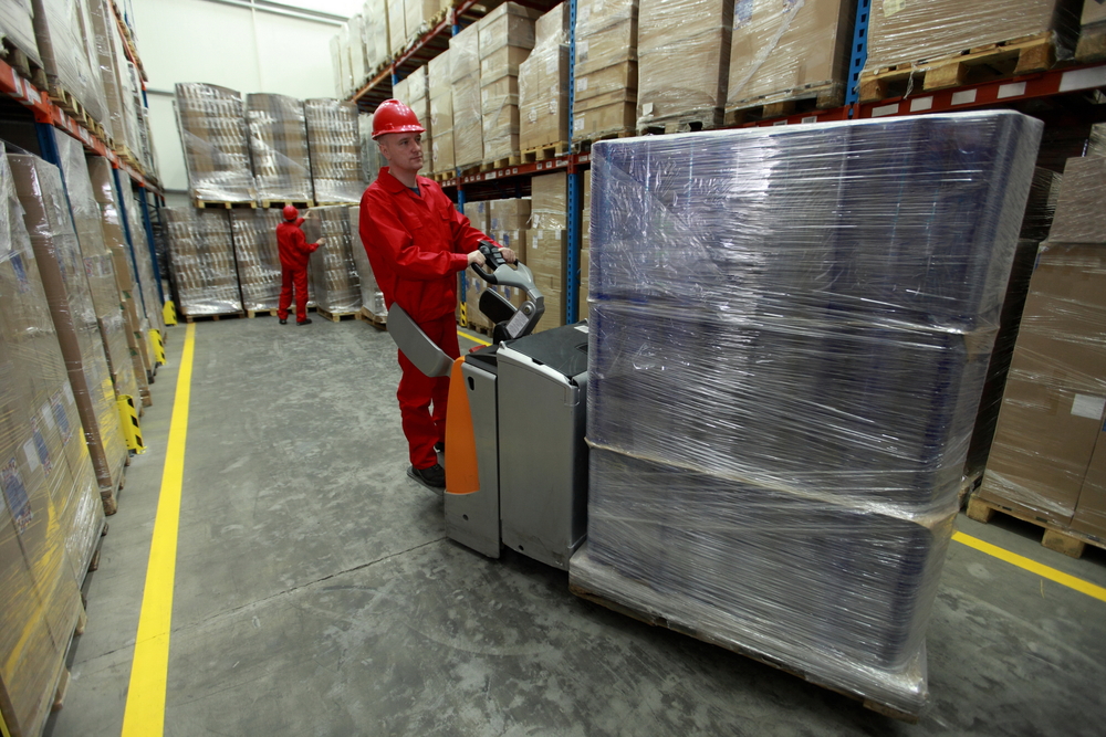 Logistics - two workers in uniforms and safety helmets working in storehouse_id427101526