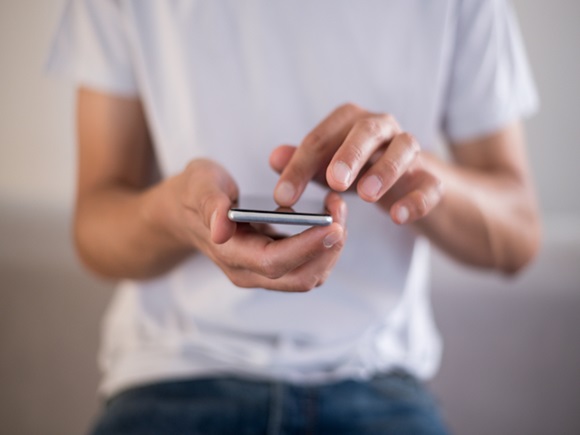 young man using smartphone, holding phone in hands, touchscreen mobile