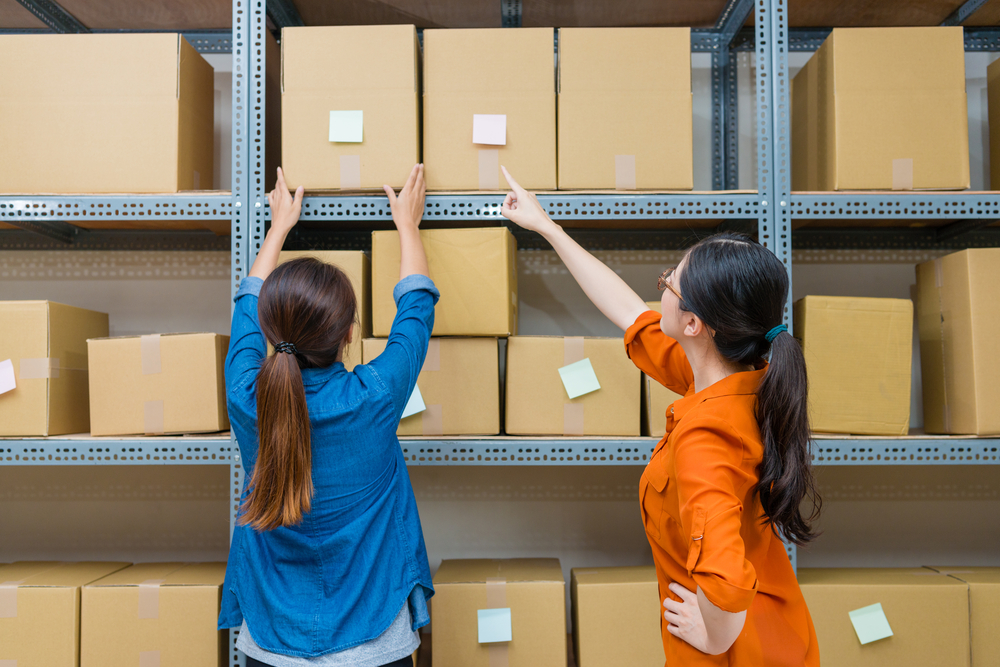 Back view photo of business team girls working together and processing online shopping order parcel box in company warehouse._id 710582737
