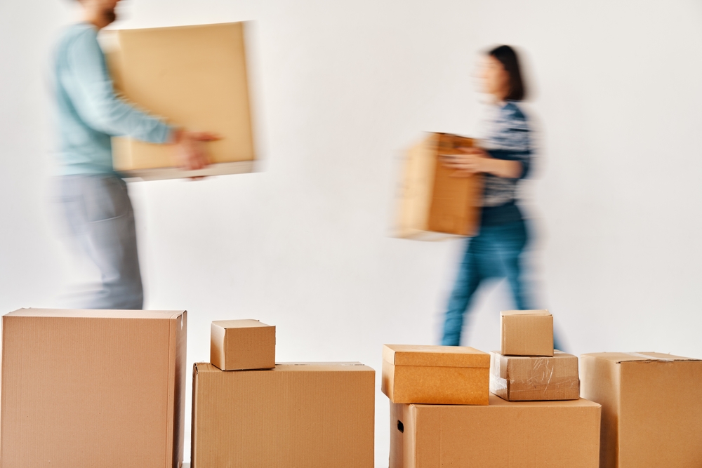 Blurred motion of young couple carrying cardboard boxes moving to new house on white background. Relocation concept_id2287109847