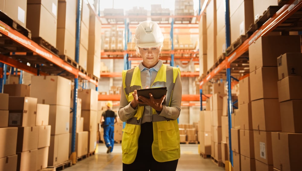 Professional Confident Worker Wearing Hard Hat Checks Stock and Inventory with Digital Tablet Computer in the Retail Warehouse full of Shelves with Goods. Working in Logistics, Distribution Center _id1845773644