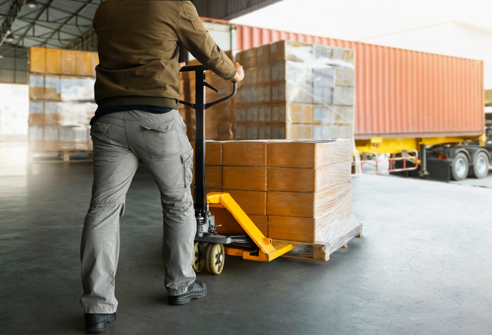 Person unloading a pallet of inventory from a shipping truck into a warehouse