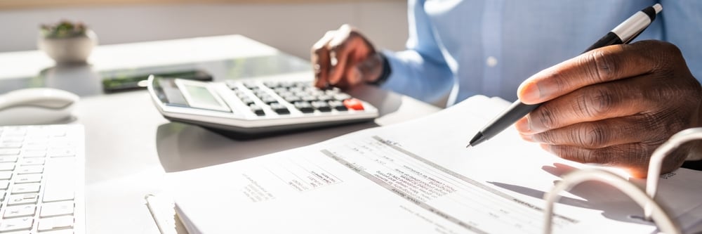 Happy Young Businessman Calculating Invoice On Computer Screen Near Laptop