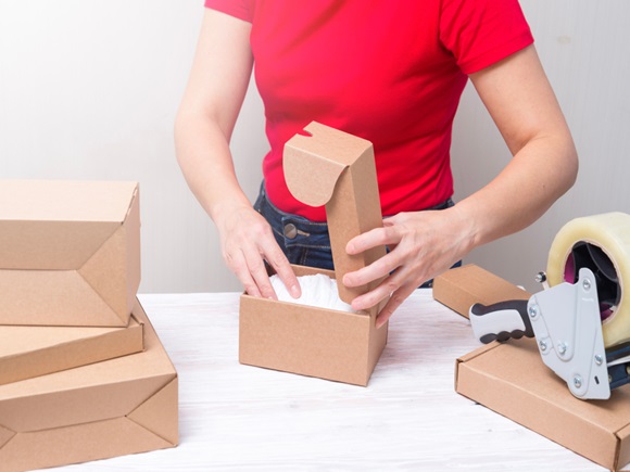 Woman packing cardboard boxes, picking and putting products_1242842272