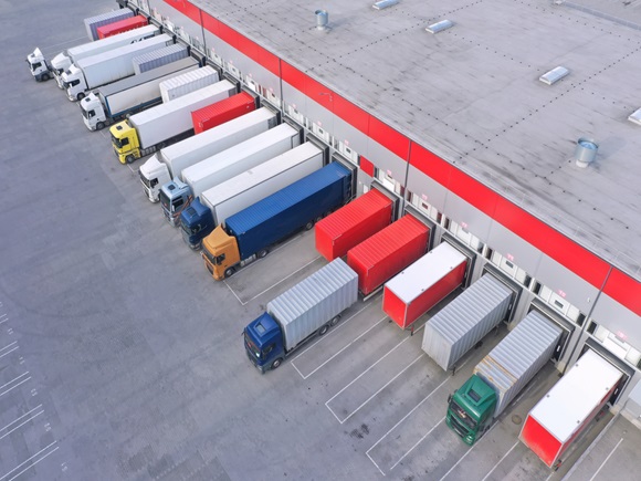 Aerial view of goods warehouse. Logistics center in industrial city zone from above. Aerial view of trucks loading at logistic center. View from drone_id1959432403