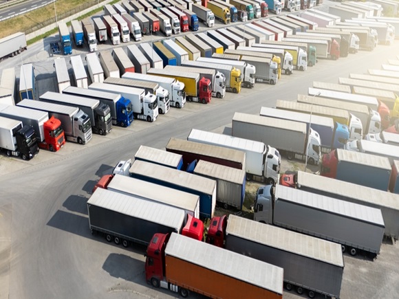 Aerial view of a large truck parking lot at a logistics hub, with multiple commercial semi trucks parked in organized rows._id2638454979