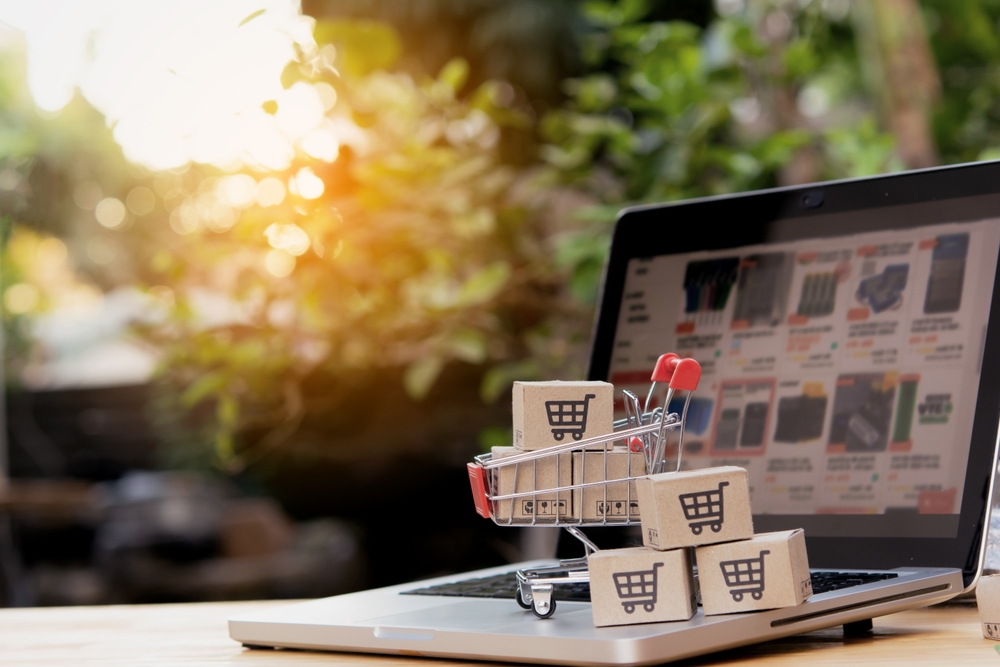 Shopping cart and packages on laptop with an ecommerce website on the screen