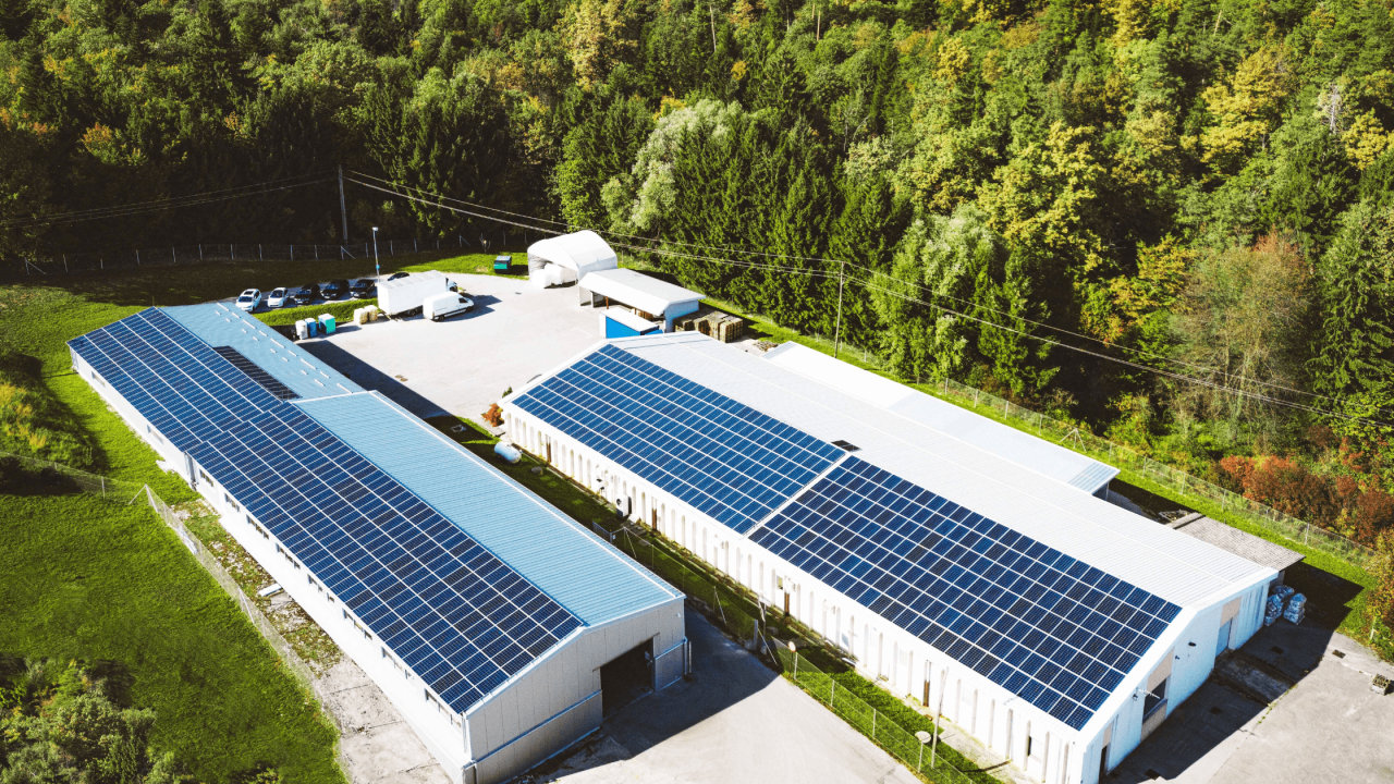An aerial view of a pair of warehouses with solar panels lining the roof.