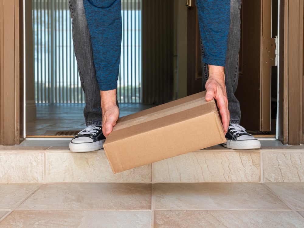 Man picking up a package box delivered to a residential doorstep. Online order package delivery to the front porch of home._id1937298901