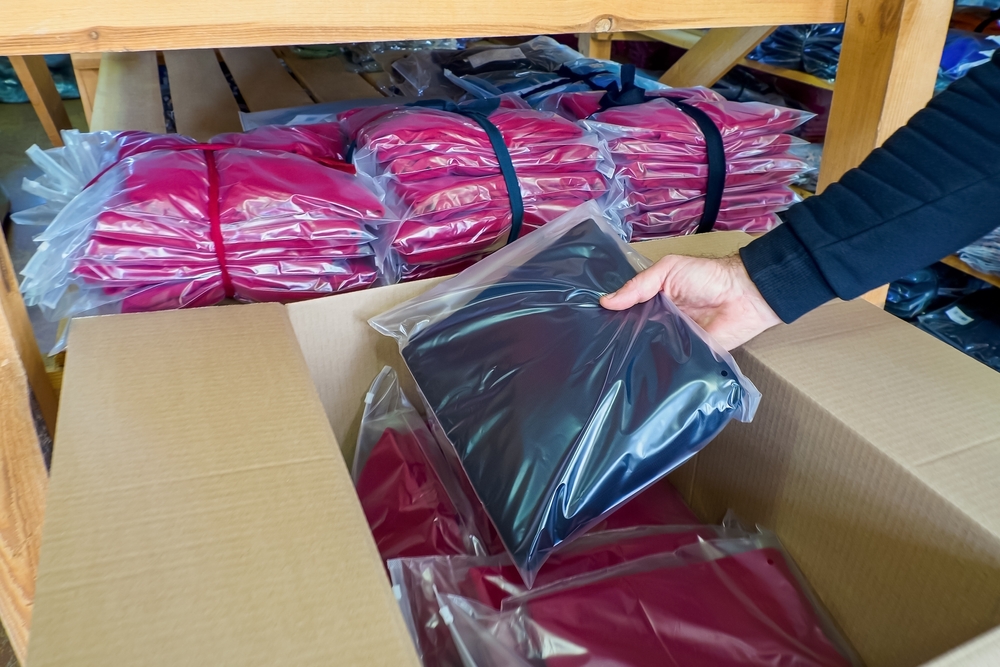 A man packs knitwear into a cardboard box for delivery and sale. Casual clothes._id2560631063