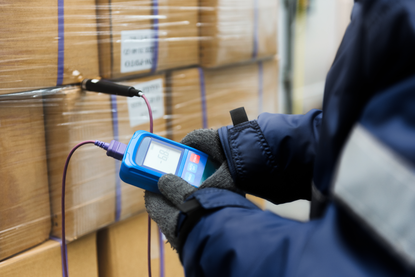 A warehouse worker monitors the temperature of inventory stored in a warehouse.
